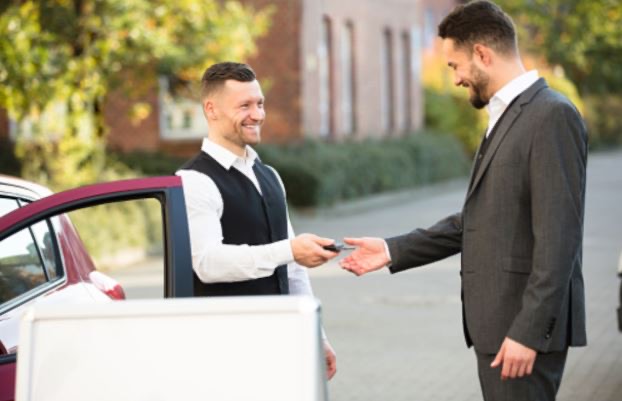 Valet attendant greeting a businessman and taking his car keys